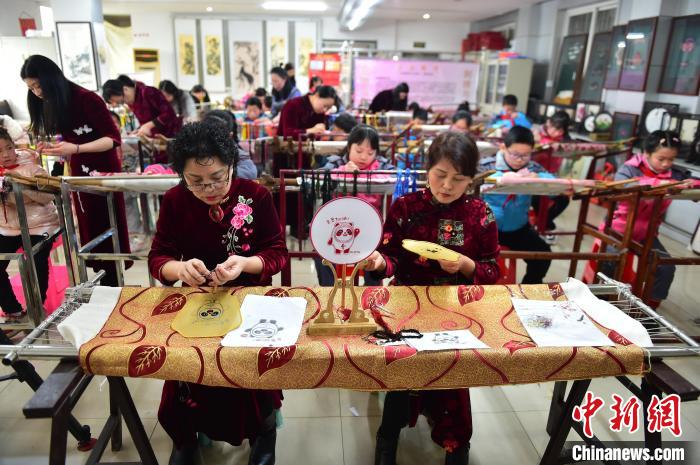 江西省級非遺豫章繡傳承人手把手指導(dǎo)小學(xué)生繡制2022年北京冬奧會吉祥物“冰墩墩”形象。　喻云亮 攝