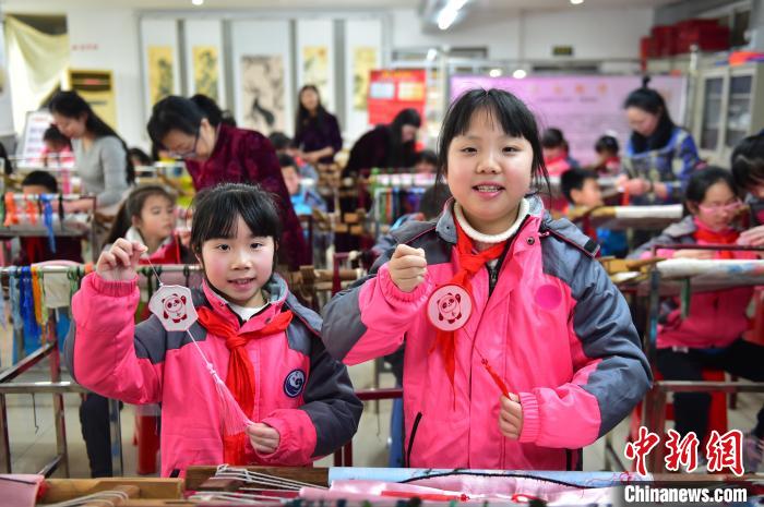 圖為小學(xué)生展示繡制好的2022年北京冬奧會吉祥物“冰墩墩”形象?！∮髟屏?攝