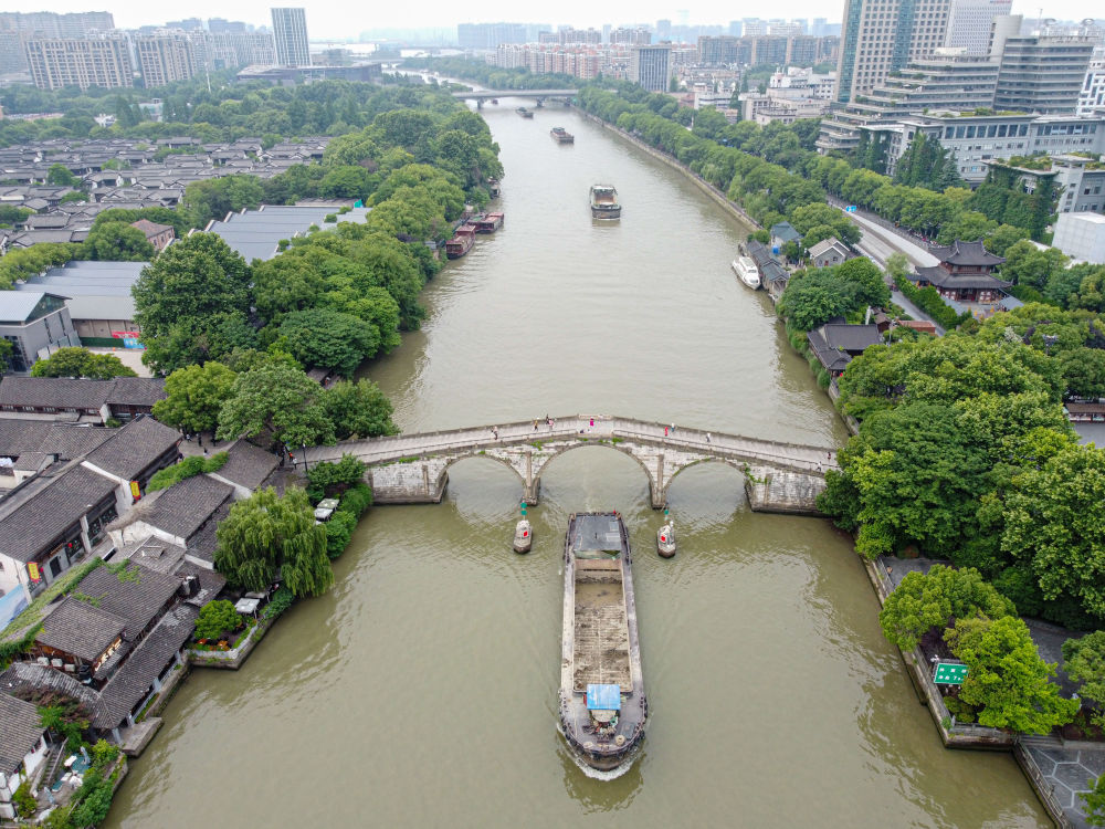 5月27日，一艘貨船駛過京杭大運河南端標(biāo)志建筑杭州拱宸橋。(無人機照片)新華社記者江漢 攝