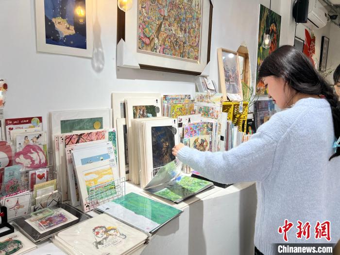 圖為藝術(shù)品商店內(nèi)，顧客挑選插畫作品?！＄婌?攝