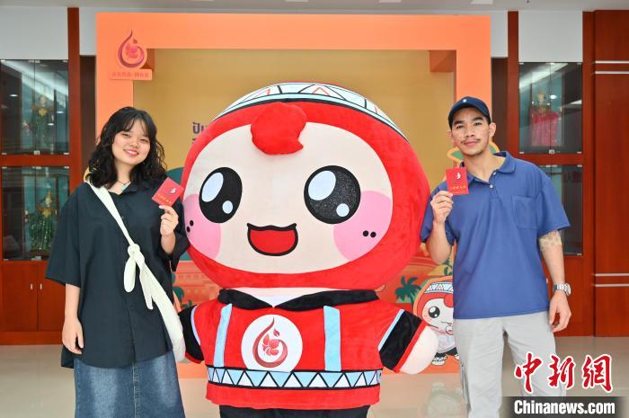 圖為泰國留學(xué)生手持獻血證與人偶合影?！∮峋?攝