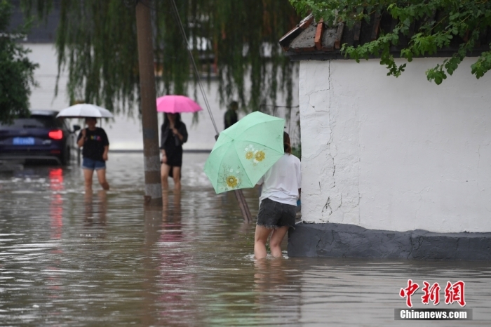 7月31日，市民行走在雨中的北京房山區(qū)瓦窯頭村。北京市氣象臺(tái)當(dāng)日10時(shí)發(fā)布分區(qū)域暴雨紅色預(yù)警信號(hào)。北京市水文總站發(fā)布洪水紅色預(yù)警，預(yù)計(jì)當(dāng)日12時(shí)至14時(shí)，房山區(qū)大石河流域?qū)⒊霈F(xiàn)紅色預(yù)警標(biāo)準(zhǔn)洪水。<a target='_blank' href='/'><p  align=