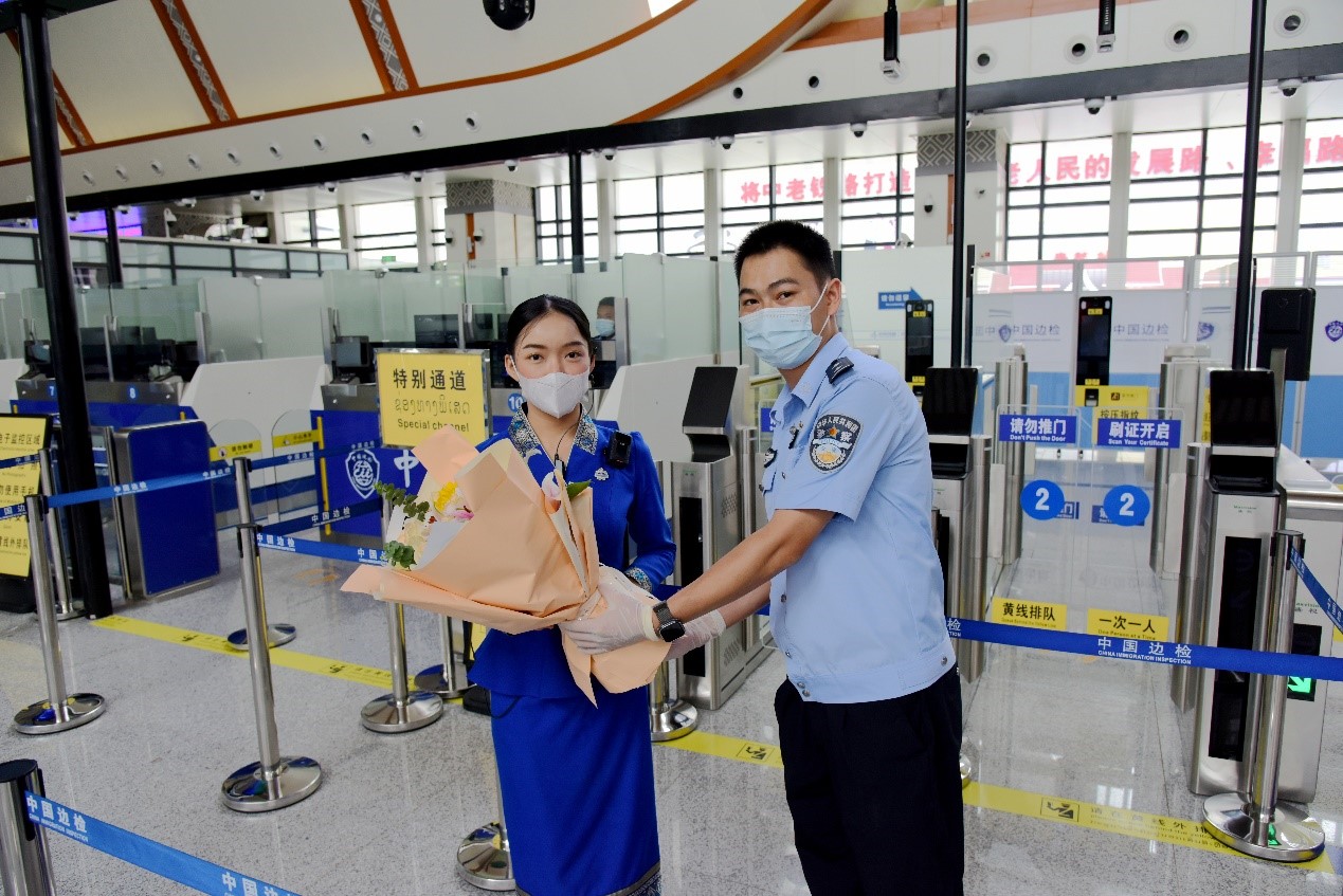 磨憨出入境邊防檢查站民警為中老鐵路第100萬名出入境旅客，D888次國際旅客列車?yán)蠐爰藙?wù)員森達(dá)拉·妮緹婭（Sengdala Nitiya），送上鮮花。黃遠(yuǎn)飛 攝