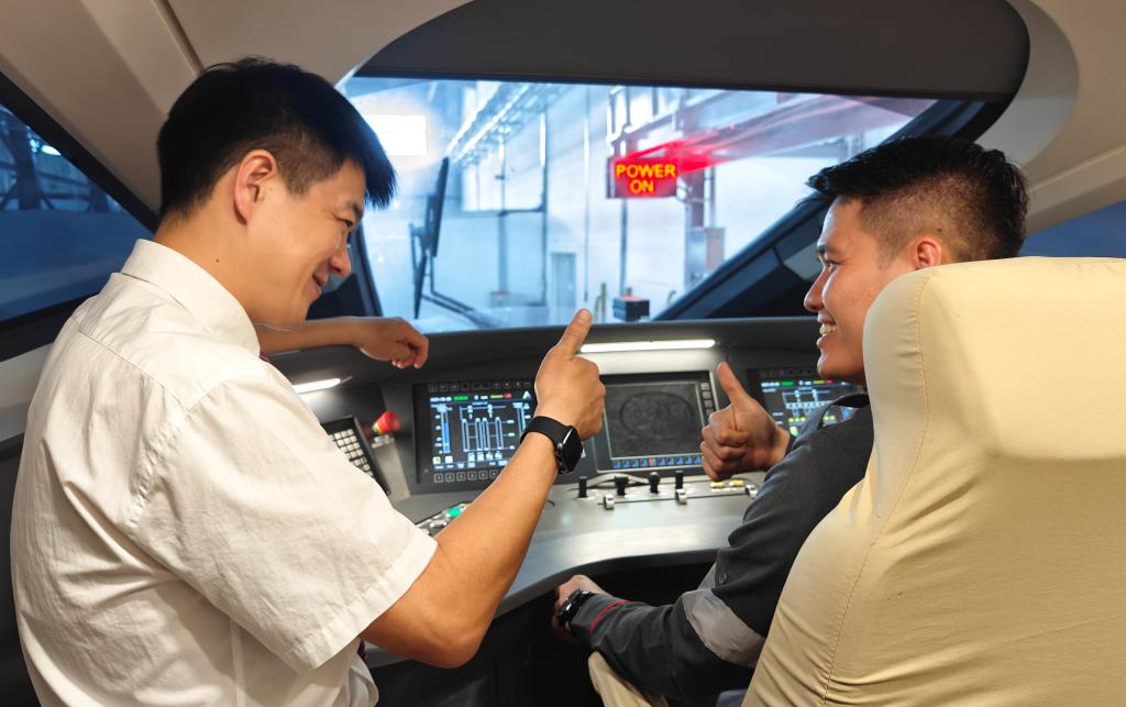8月25日，在印度尼西亞萬隆的雅萬高鐵德卡魯爾動車所內(nèi)，中國師傅穆振（左）在向印尼火車司機(jī)塞蒂亞萬講解動車組出庫前的上電作業(yè)。
