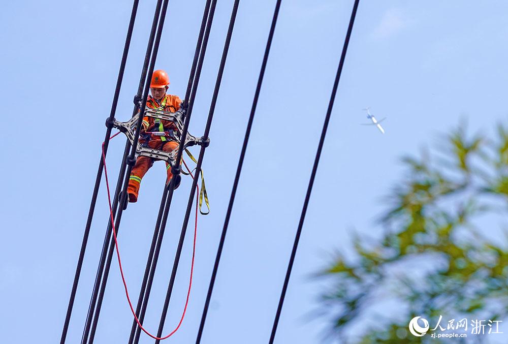 3月11日，在浙江省諸暨市河上鎮(zhèn)，浙江省送變電工程有限公司檢修人員在高空的導(dǎo)線上進行線路檢修維護。人民網(wǎng) 章勇濤攝