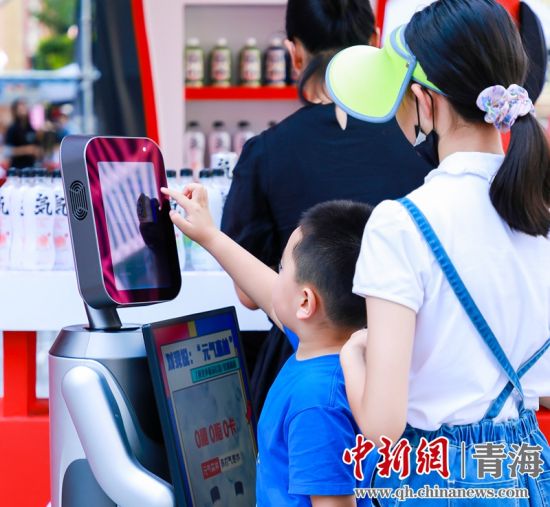 圖為一名小朋友正在和機(jī)器人“志愿者”進(jìn)行互動(dòng)。 沐聞 攝