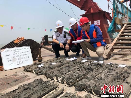 圖為勘察設(shè)計人員與海事局工作人員查看巖芯情況?！∥赫?攝
