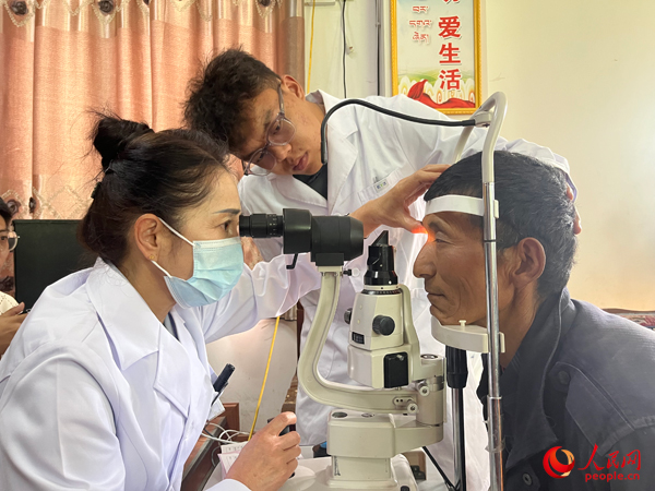 王紅英（左）和團(tuán)隊(duì)成員為達(dá)熱村村民檢查眼睛。人民網(wǎng)記者 杜燕飛攝