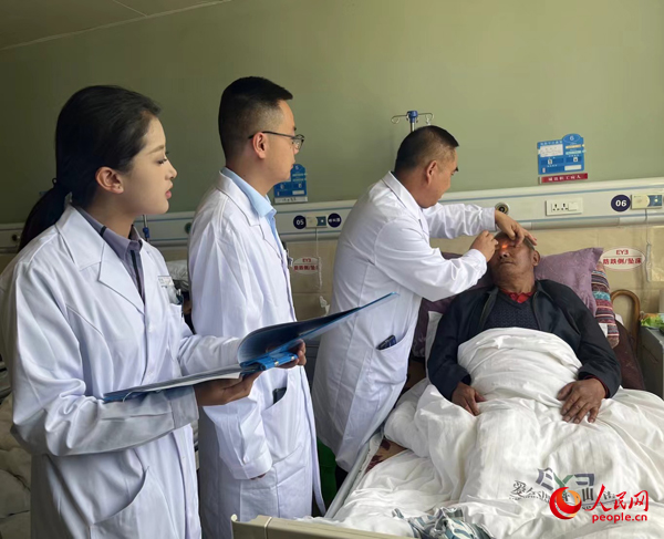 董光明（左三）帶領(lǐng)醫(yī)生對患者進(jìn)行術(shù)前檢查。人民網(wǎng)記者 杜燕飛攝