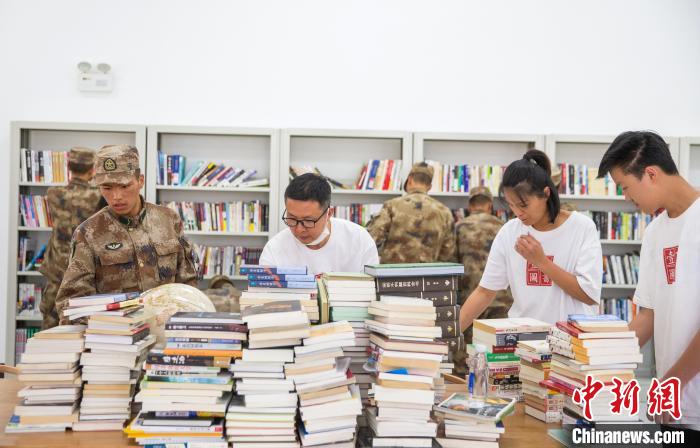 圖為志愿者們和邊防戰(zhàn)士整理圖書?！詵| 攝