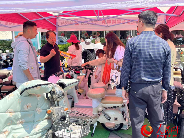 某電動自行車品牌工作人員向消費者介紹以舊換新相關(guān)情況。人民網(wǎng)記者 杜燕飛攝