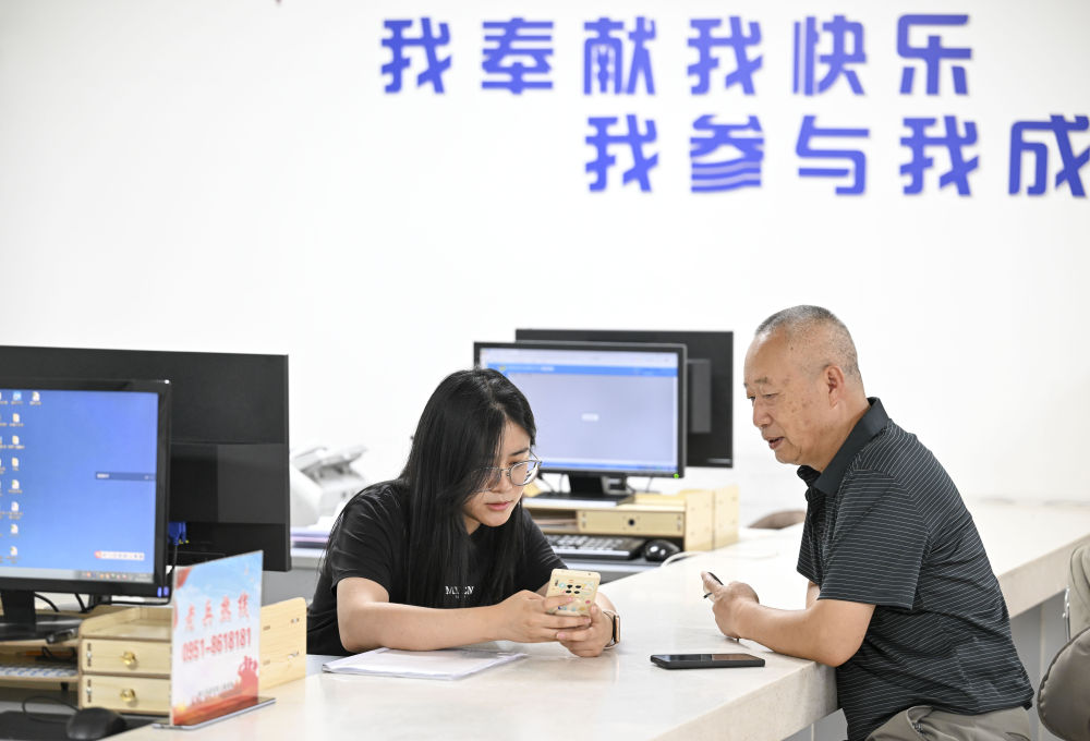 2024年6月20日，在寧夏銀川市金鳳區(qū)長(zhǎng)城花園社區(qū)黨群服務(wù)中心，工作人員幫助居民辦理業(yè)務(wù)。圖片來(lái)源 新華社