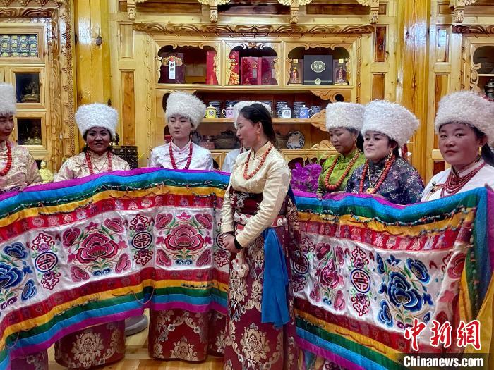 圖為女性展示村民自發(fā)繡制的“百米五彩哈達”?！±钣穹?攝