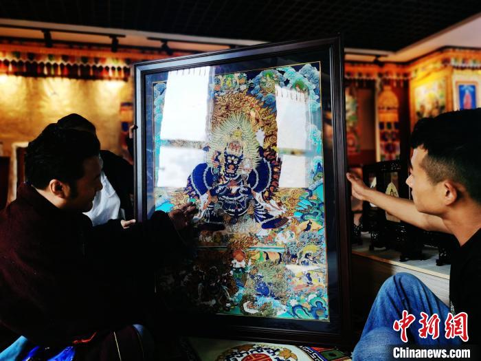 圖為久美尖措(左)與徒弟們展示唐卡作品?！?zhí)砀?攝