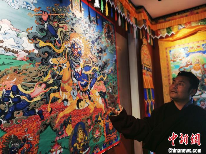 圖為久美尖措展示唐卡作品?！?zhí)砀?攝