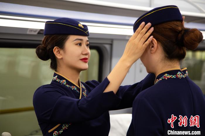 圖為青藏鐵路西格段“復(fù)興號”動車組乘務(wù)員互相整理新制服?！±罾?攝