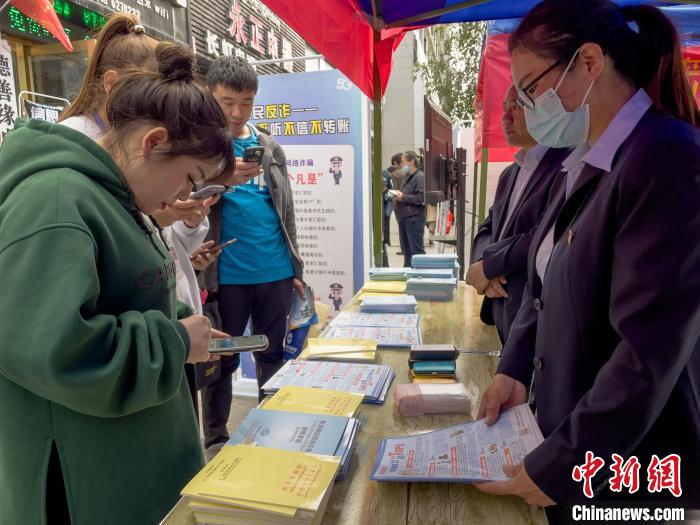 圖為工作人員正在向路過市民介紹國(guó)家反詐中心軟件的功能。　謝牧 攝