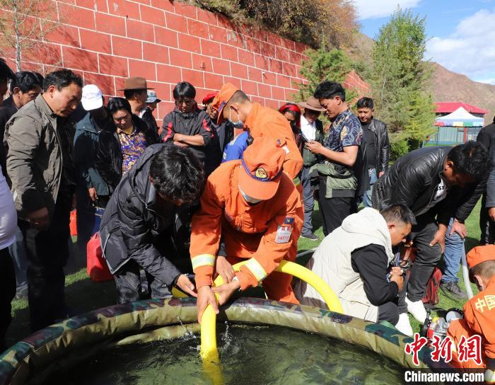 圖為森林消防員為護(hù)林員講解滅火裝備的使用方法?！〔际猩窒乐ш?duì) 供圖