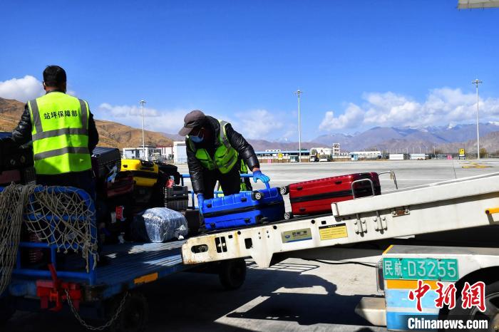 圖為機(jī)場工作人員傳送旅客行李箱?！≈芎?攝