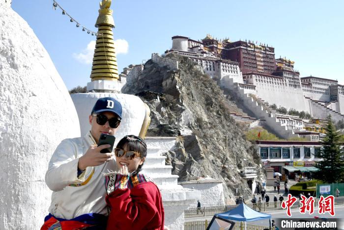 4月17日，游客身著藏式元素服裝在拉薩布達(dá)拉宮觀景臺(tái)拍照留念?！±盍?攝