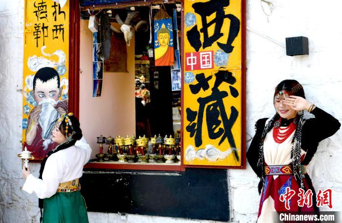 4月17日，游客身著藏式元素服裝在拉薩八廓街拍照留念。　李林 攝