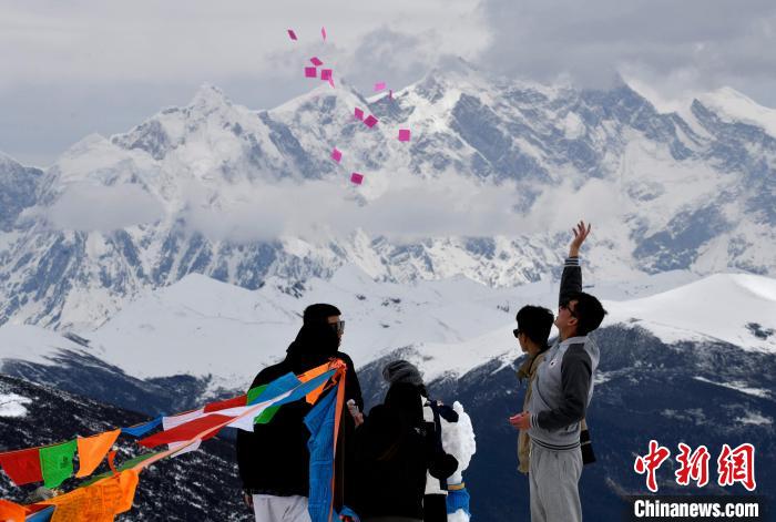 圖為5月14日，游客在西藏林芝色季拉山觀景臺(tái)拋灑“隆達(dá)”(風(fēng)馬旗，藏族民眾的一種祈福方式)?！±盍?攝