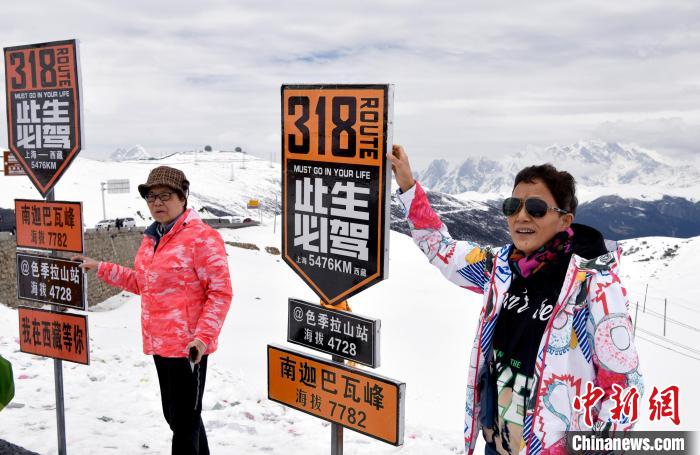 圖為5月14日，西藏林芝色季拉山觀景臺(tái)，游客與南迦巴瓦峰合影。　李林 攝